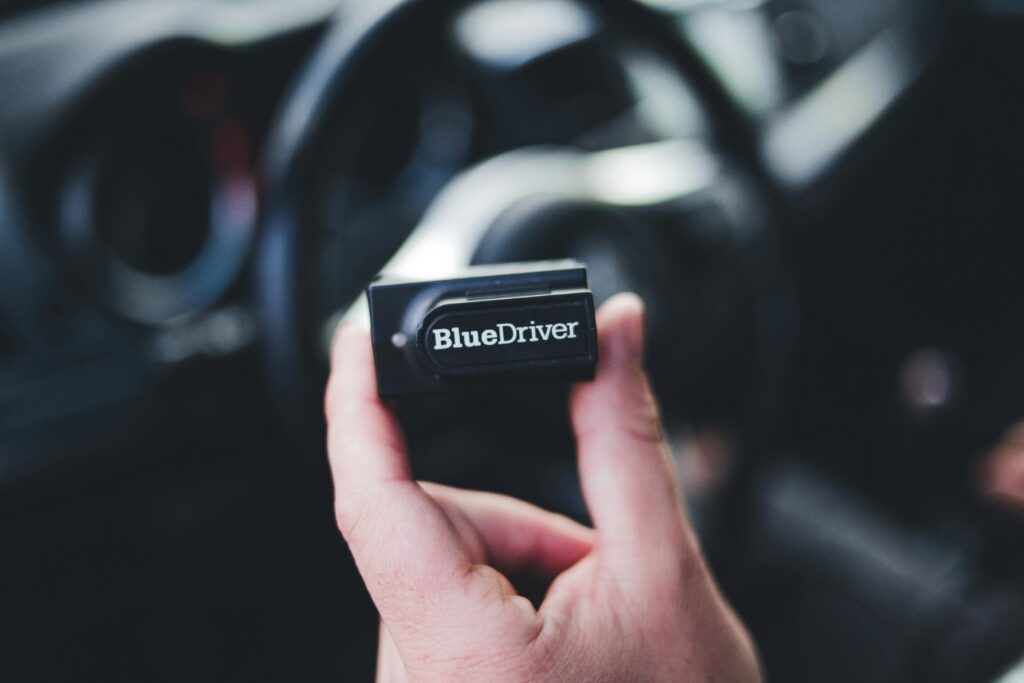 Detailed image of a hand holding a Bluedriver OBD2 scanner inside a car.